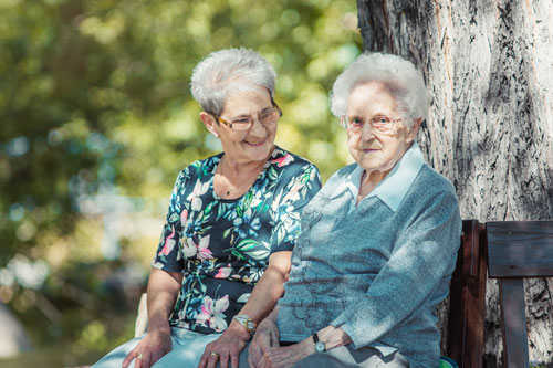 Zwei Seniorinnen sitzen auf einer Bank