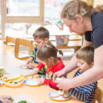 Ein Erzieher schneidet zusammen mit Kindern Obst