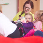 Eine Erzieherin und mehrere Kinder sitzen auf dem Sofa