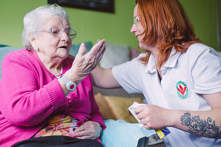 Pflegerin unterhält sich mit einer Rentnerin