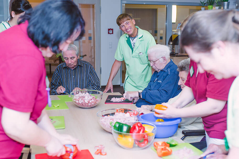 Pfleger bereiten mit Senioren Essen zu
