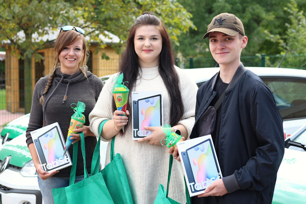 Drei Auszubildende der Leipziger Volkssolidarität mit Zuckertüte und Tablet in der Hand
