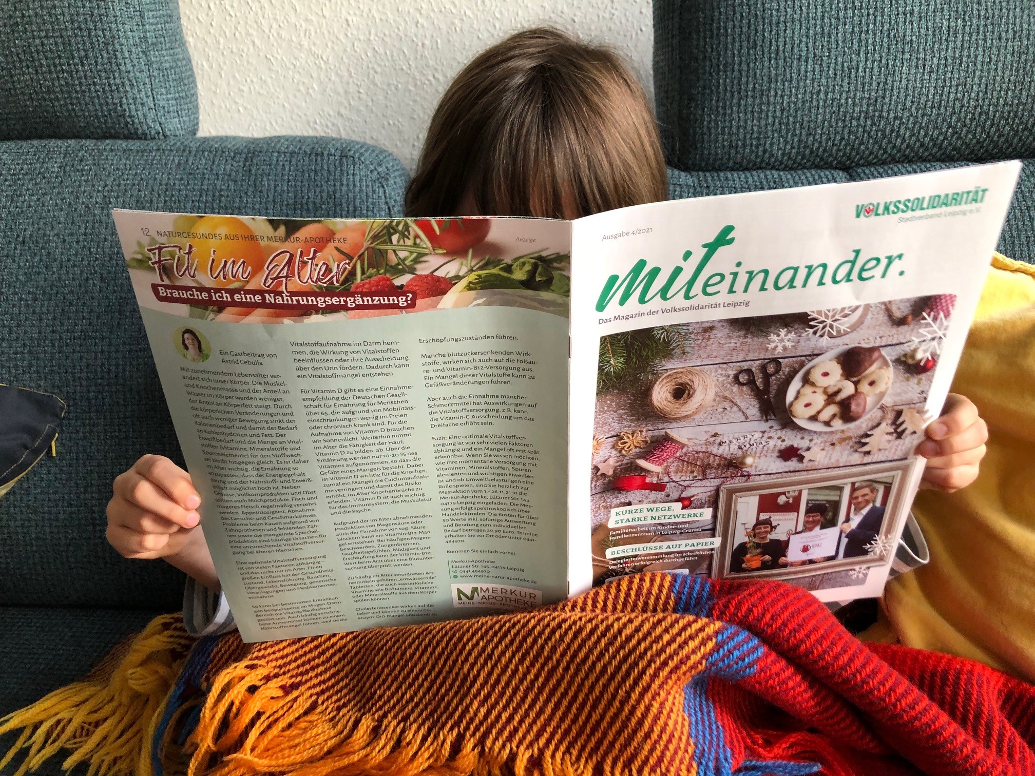 Kind liest neue Ausgabe des Magazins MITEINANDER auf der Couch.