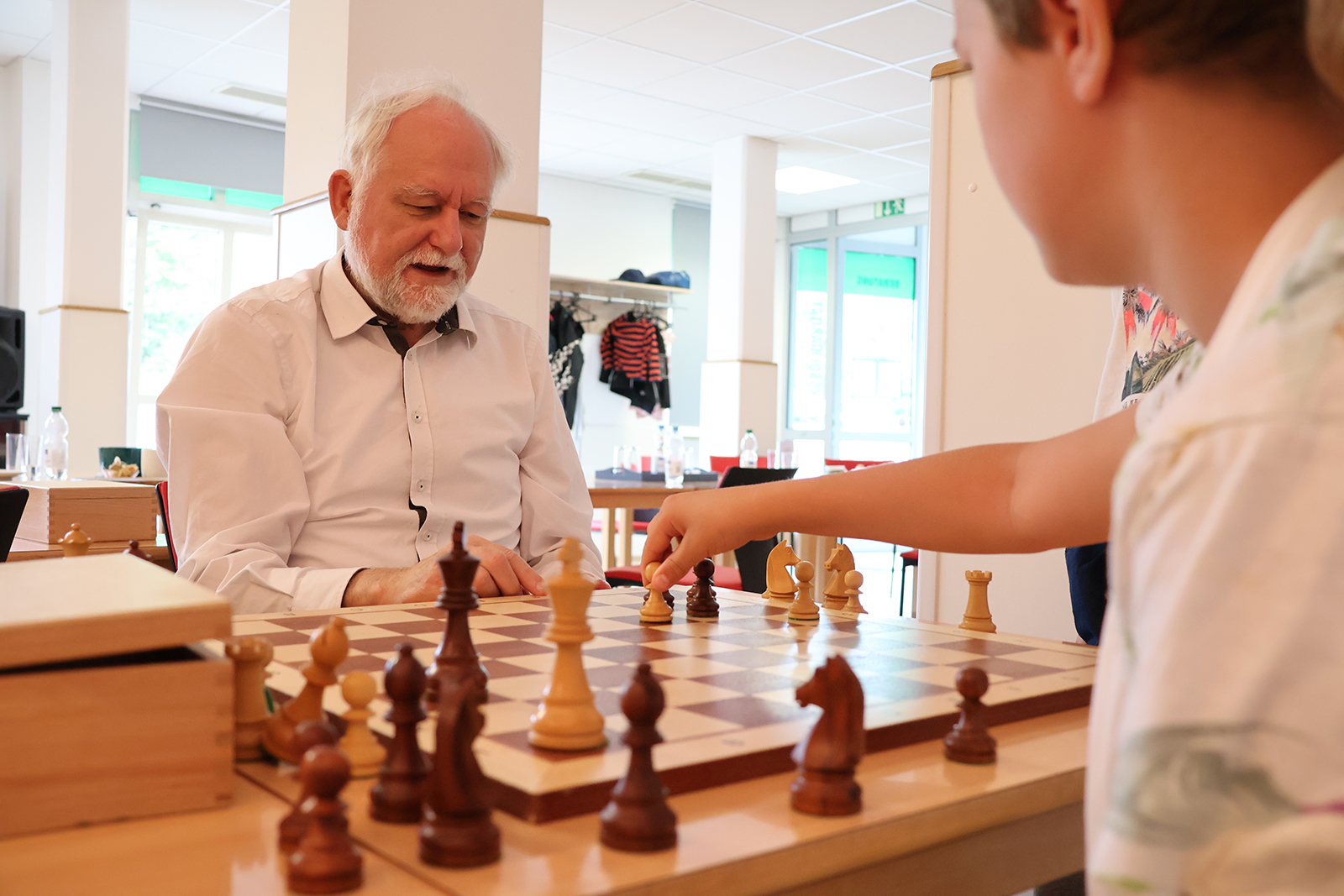 Jürgen Rudolph rückt mit einem Schüler die Schachfiguren strategisch übers Brett. (Foto: Ulrike Gierth)