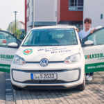 Pflegerin steht hinter geöffneter Autotür an einem Fahrzeug mit dem Aufdruck der Volkssolidarität.