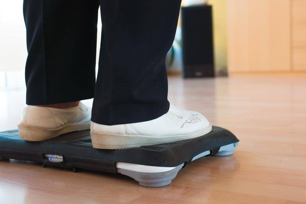 Die Füße einer Seniorin stehen auf einem Wii Balance Board.