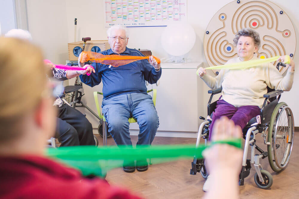 Senioren führen leichte Sportübungen mit Tüchern durch.